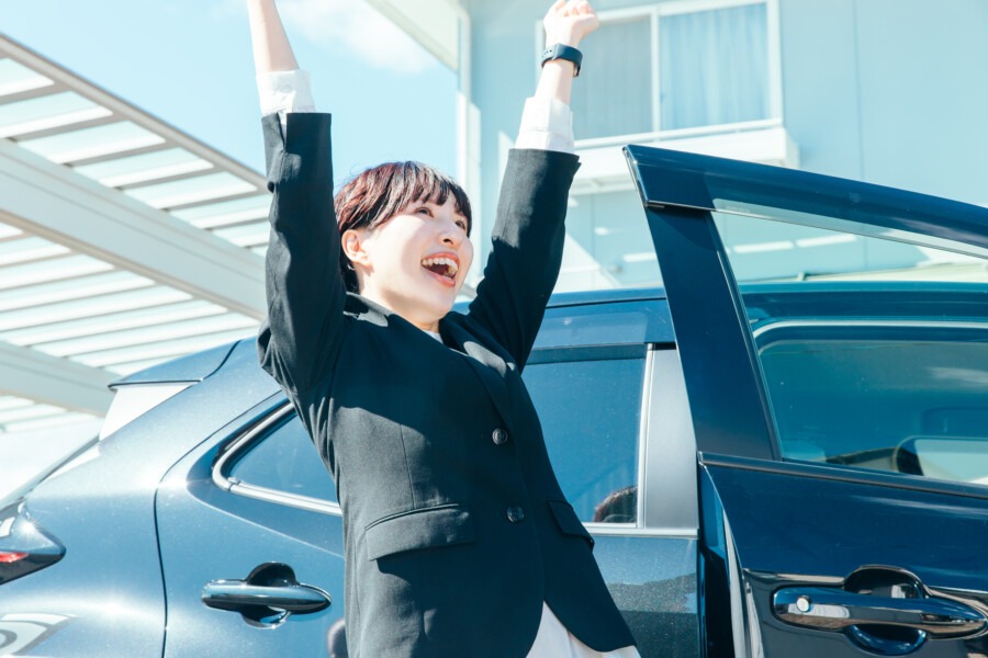 営業車からおりて背伸びをする営業